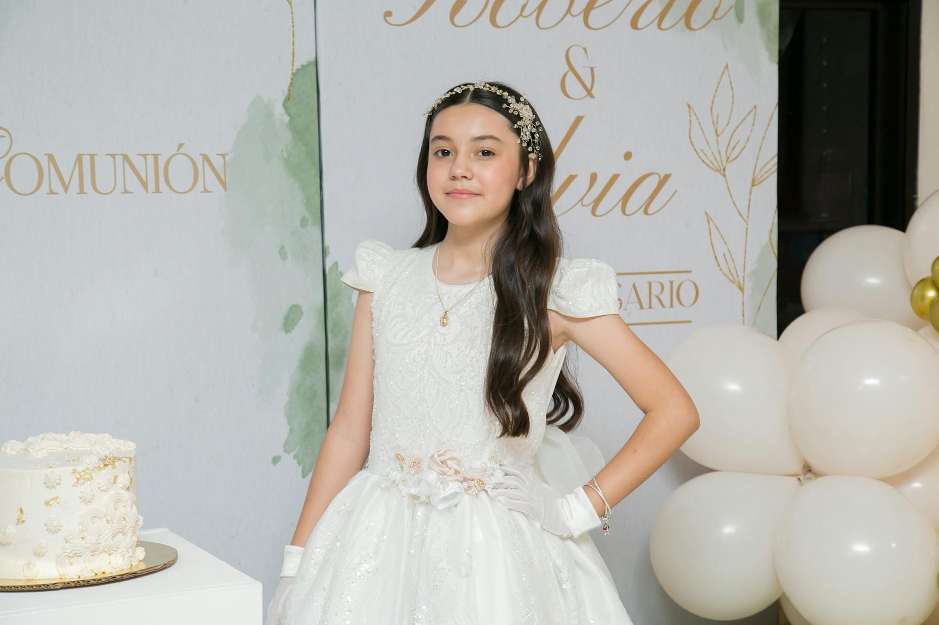 Dziewczynka w sukience komunijnej przy torcie i białych dekoracjach