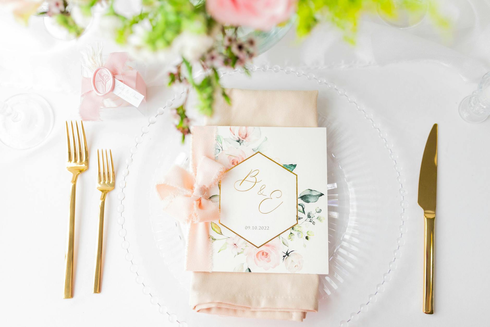 Eleganckie zaproszenie ślubne na stole z kwiatami i złotymi sztućcami