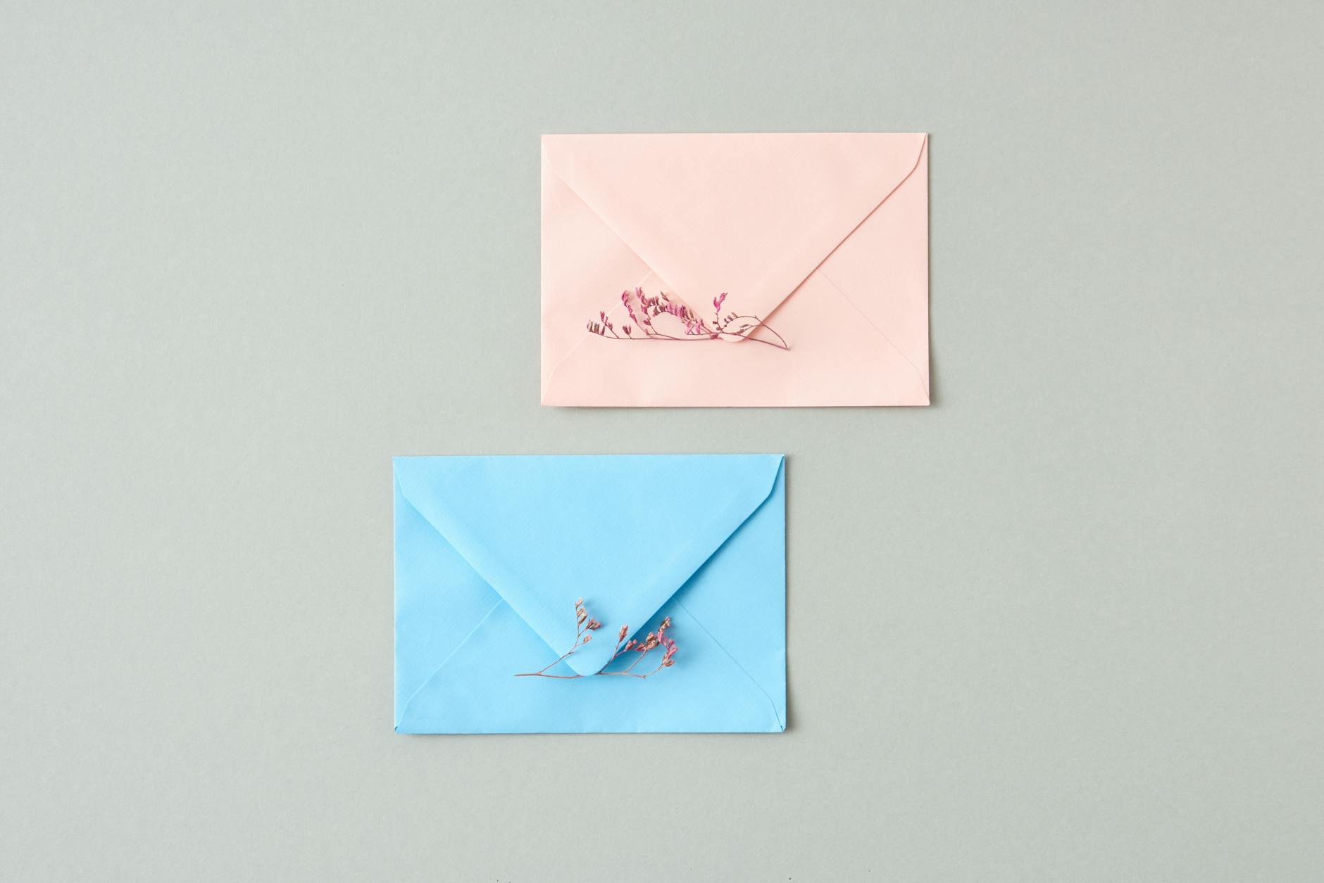 Pastelowe koperty do zaproszeń na chrzest z minimalistyczną papeterią i kwiatami