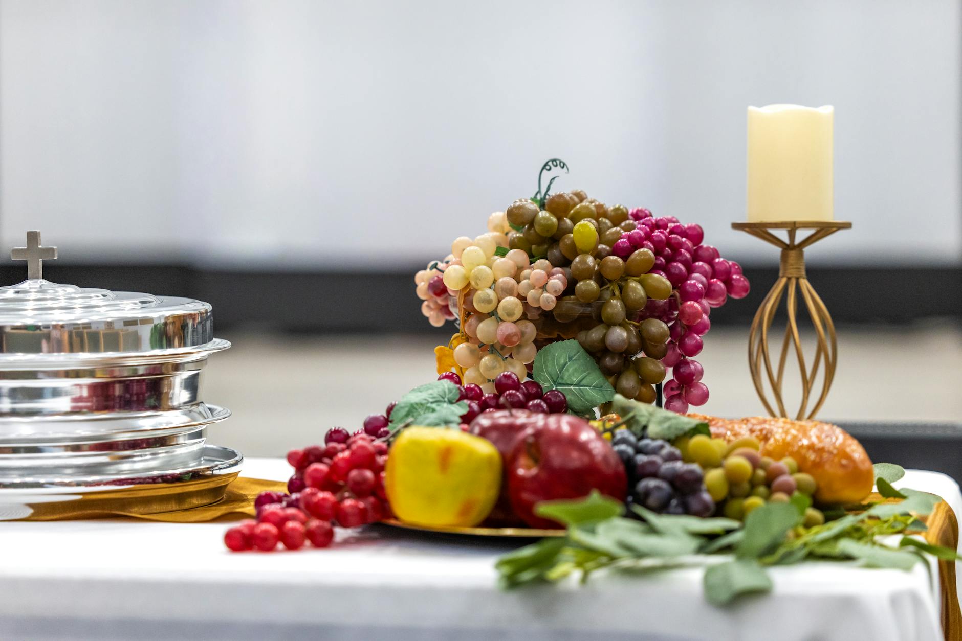 Stół komunijny z owocami, świecą i symbolami pierwszej komunii