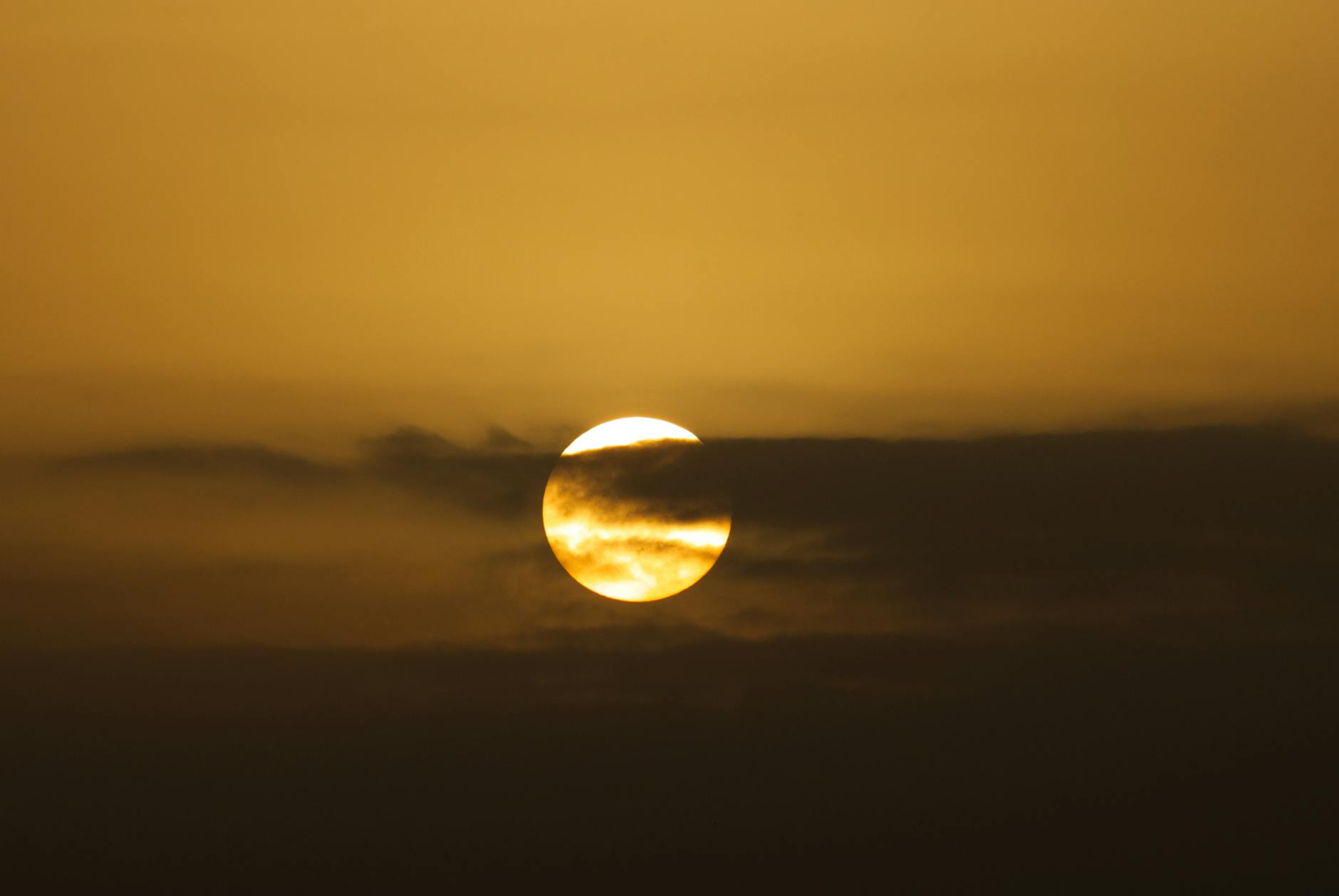 Złote słońce zachodzące za bursztynowymi chmurami na dramatycznym niebie